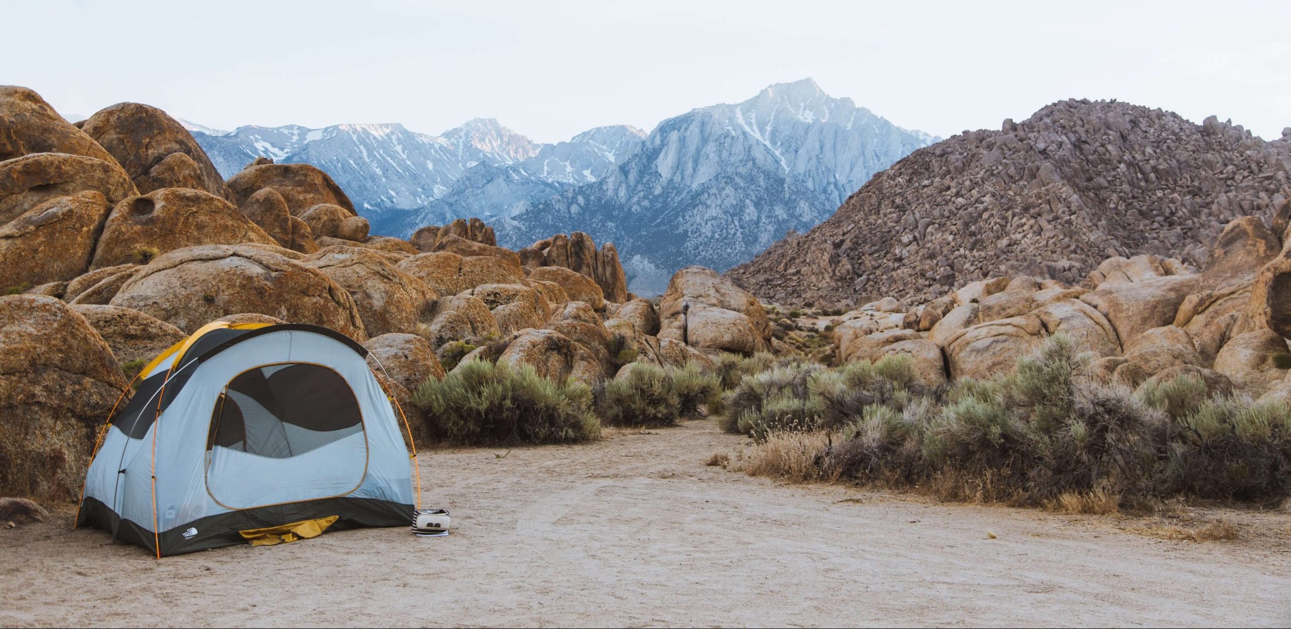 Photo of a tent pitched in the mountains, which a Girl Scout troupe is using to camp during a trip