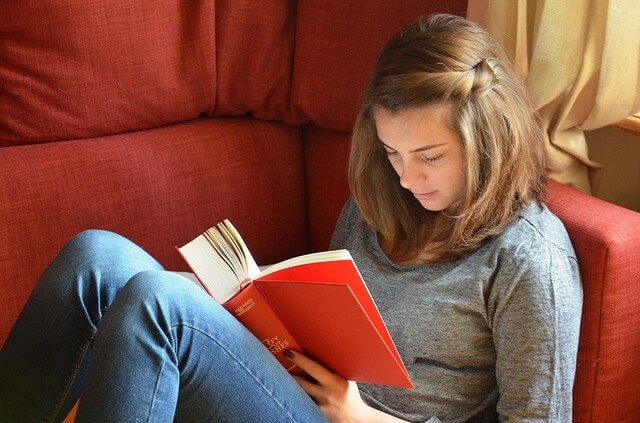 High school freshman reads a book after applying to a scholarship