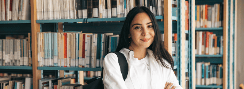 Smiling student who received LGBTQ scholarships stands in a library