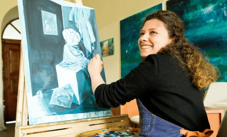 Woman who received an art scholarship paints a picture in class